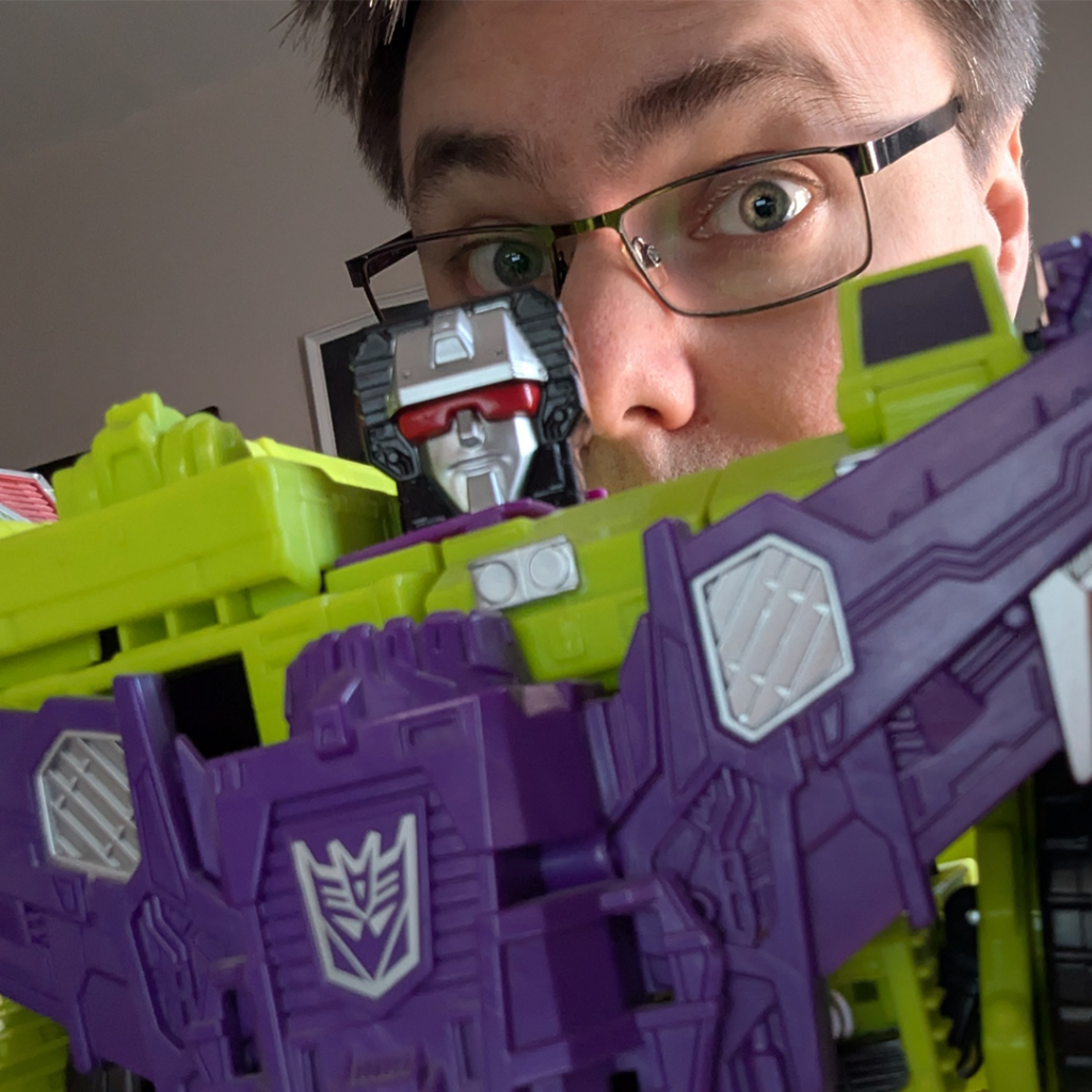 Matthew posing with a transformers toy of Devastator